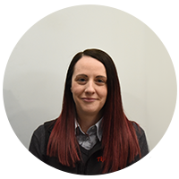Joanne young female with long dark red hair smiling. wearing dark clothes